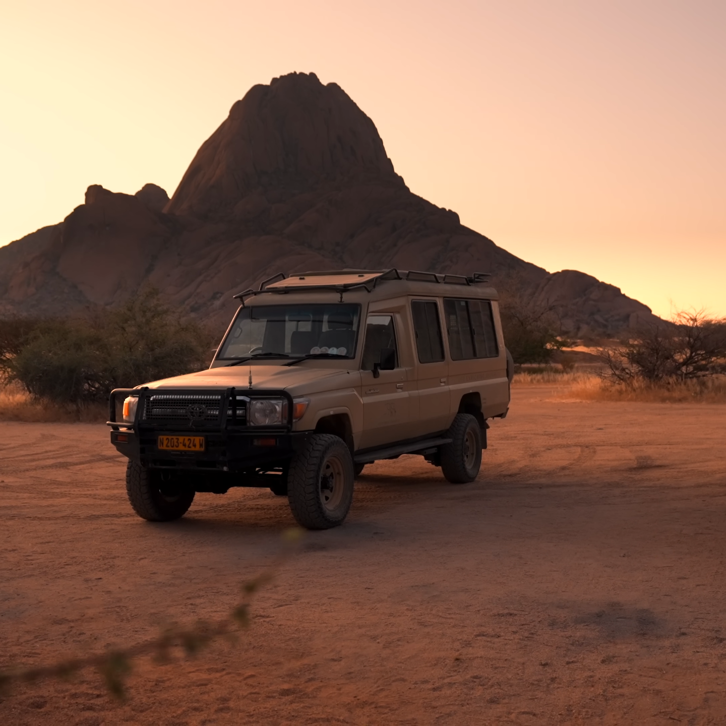 Two safari Toyota Land Cruisers parked at sunset with Spitzkoppe mountain in the background, Namibia_Car Rental Road Trips