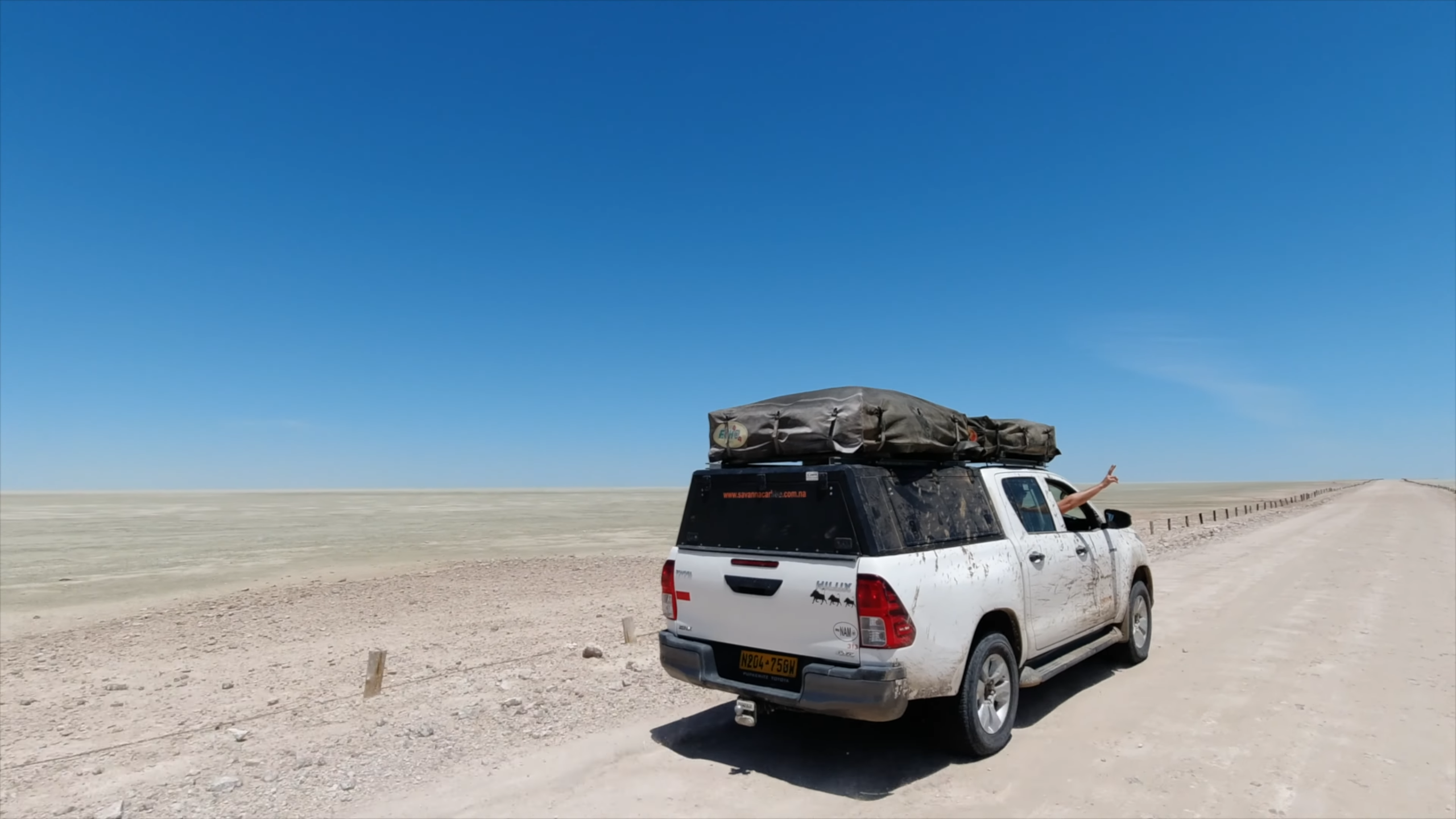 4x4 vehicle Totyota Hilux with rooftop tent driving on a remote desert road under a clear blue sky in Namibia_10-Day Namibia Self-Drive Safari_Car Rental Road Trips